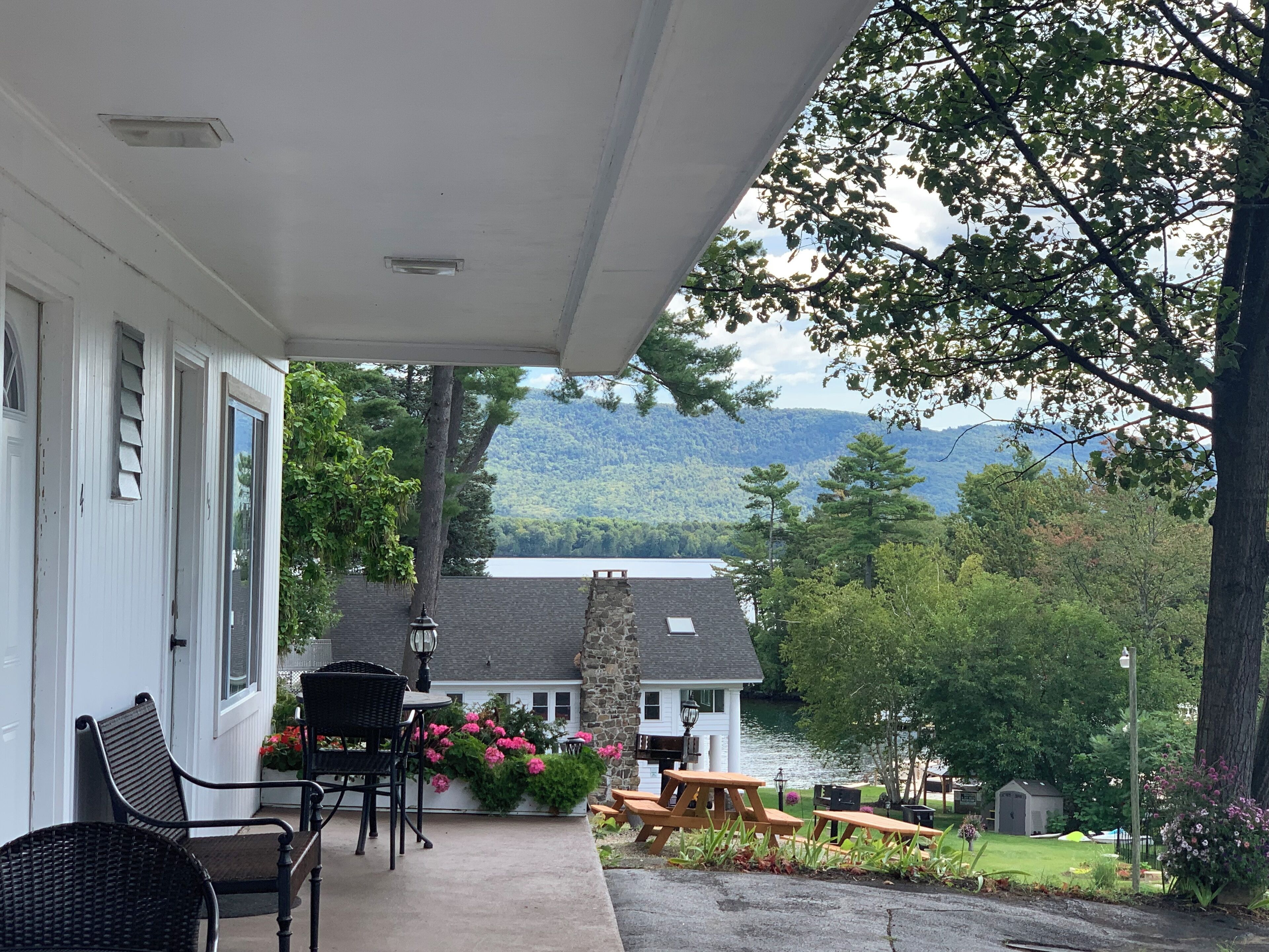 A covered porch with outdoor seating, a stone wall, and a view of a lake and mountains.