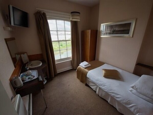 Habitación de hotel con cama, mesita de noche, televisión, ventana y baño.
