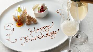 Ein weißer Teller mit einer Dessertanrichtung und eine Champagnerflasche, aus der Sekt in ein Glas gegossen wird.