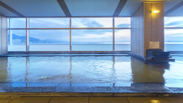 A large indoor swimming pool with a view of a body of water and mountains through large windows. - Biwako Hotel (Otsu)