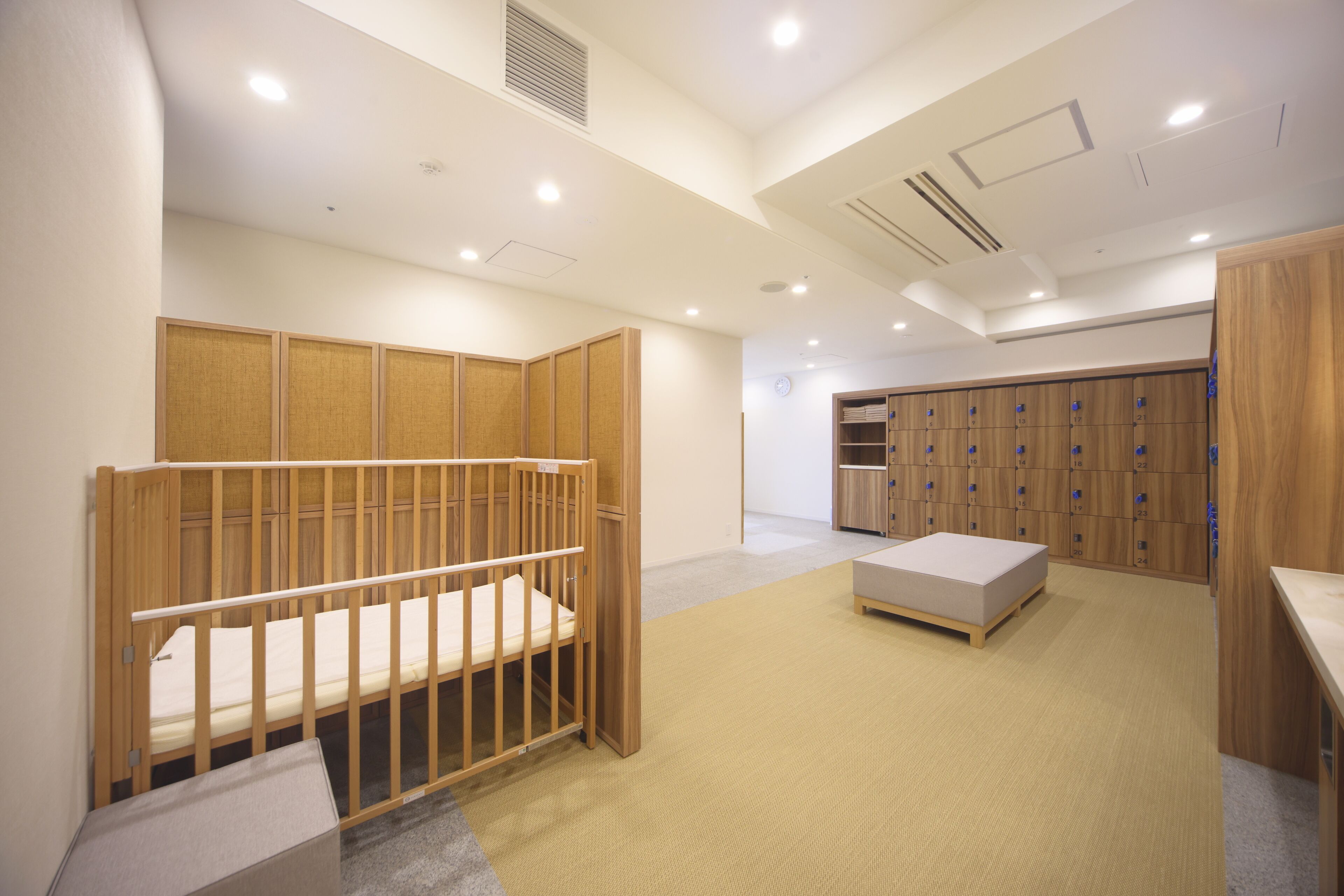 A room with a wooden crib, a small bed, a storage unit, and a locker area.