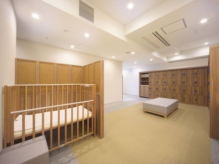 A room with a wooden crib, a small bed, a storage unit, and a locker area.