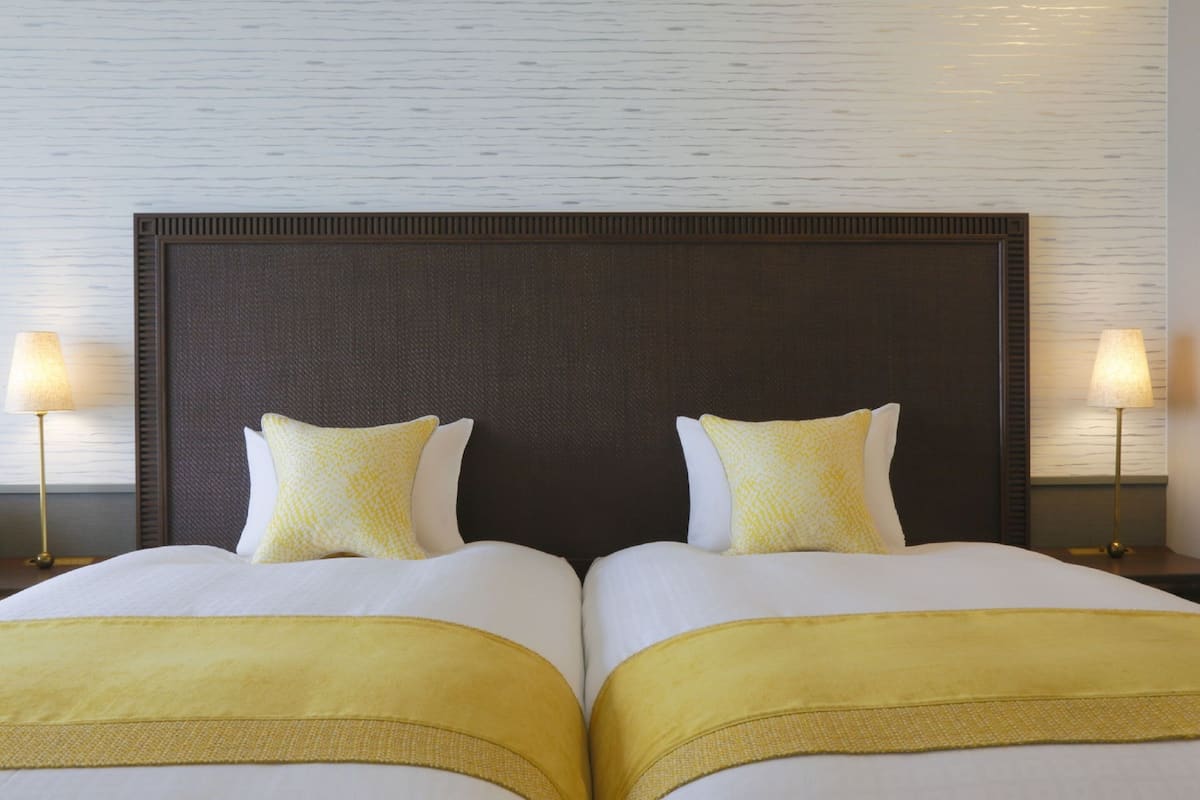 A double bed with a dark headboard, two pillows, and a yellow throw blanket.