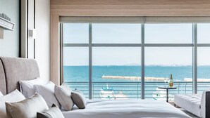 A hotel room with a large bed, a view of the sea, and a table with a bottle. - Biwako Hotel (Otsu)