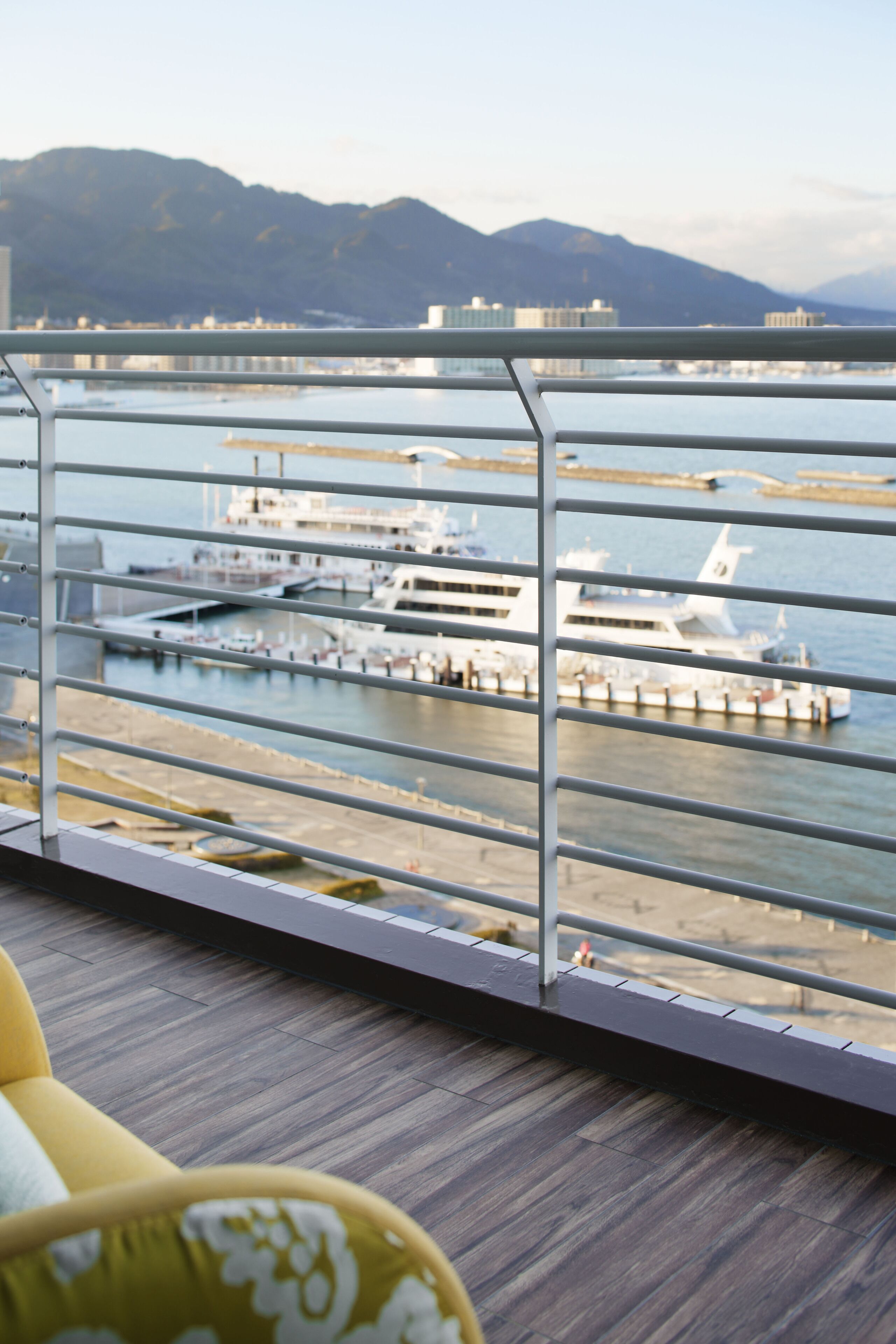 A balcony with a view of a marina, featuring boats docked at the pier.