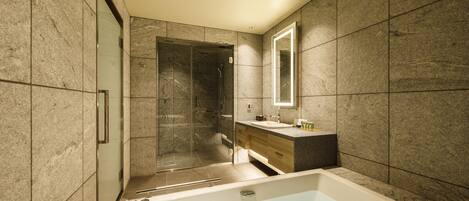 A modern bathroom with a large bathtub, a glass-enclosed shower, and a vanity with a mirror.