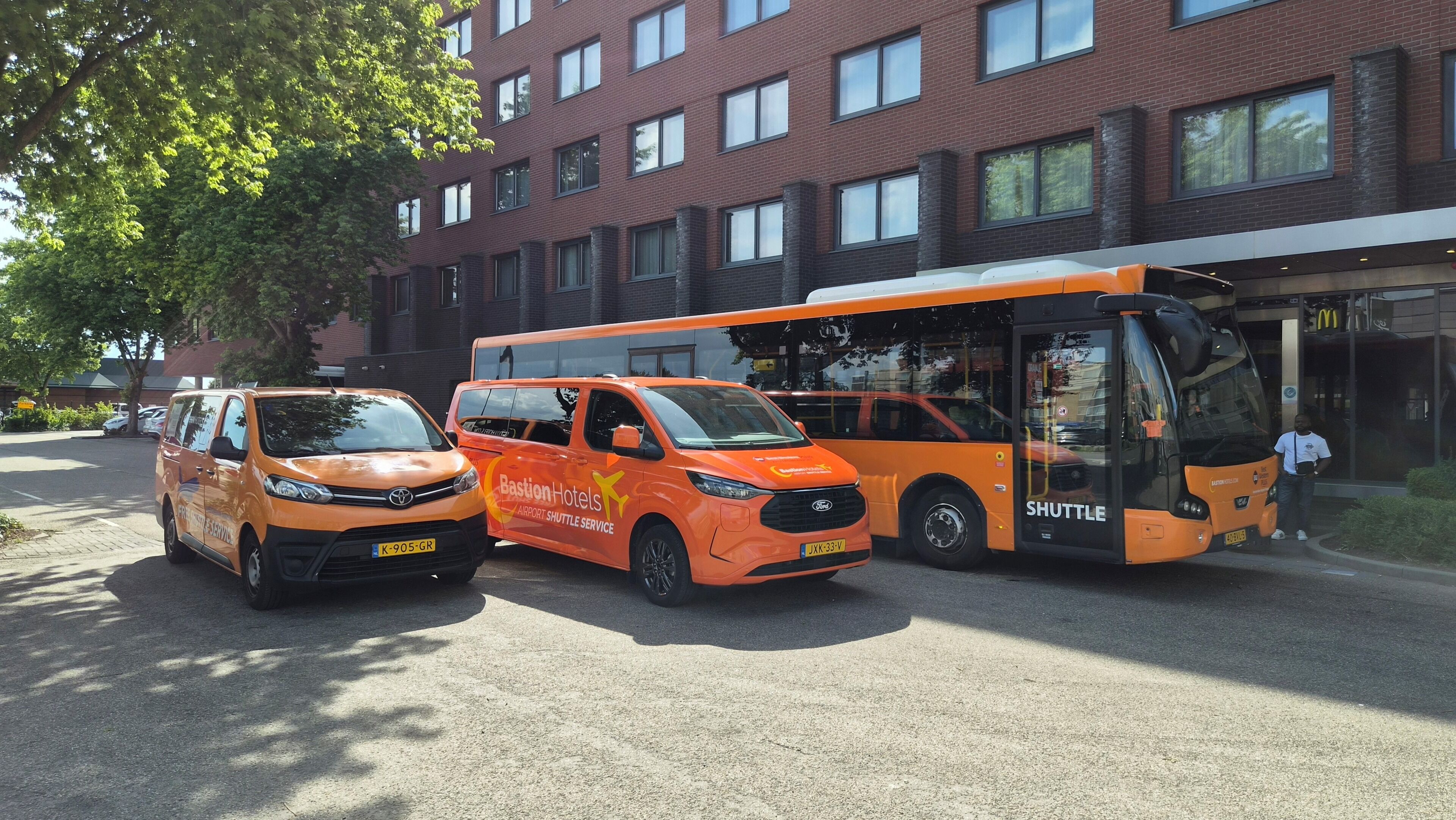 Vehículo de servicio de transporte estacionado frente a un edificio con fachada de ladrillo y varias ventanas.