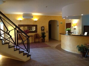A hotel lobby with a staircase, reception desk, and a wall-mounted clock. - Hotel Rural Monte Da Leziria (Santiago do Cacém)