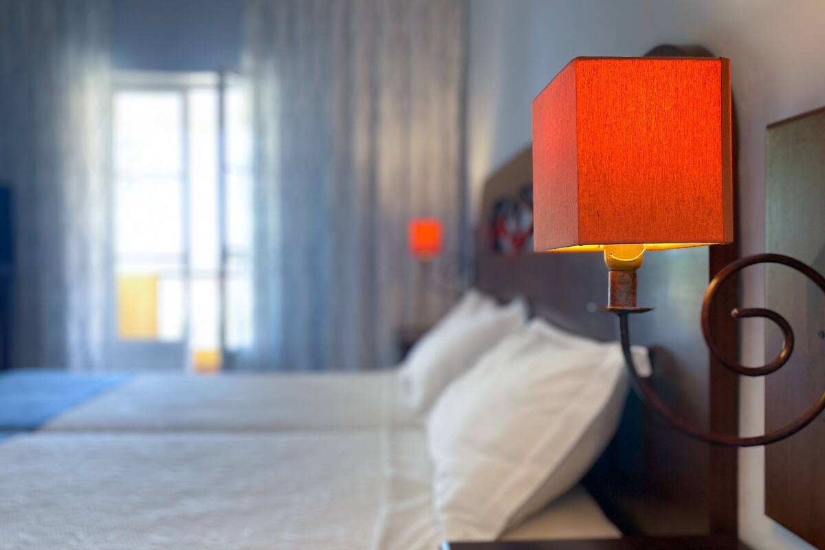 Una habitació d'hotel amb un llit, una taula de nit i una làmpada penjada a la paret.