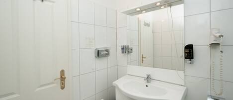 A modern bathroom with a white sink, a mirror, a towel rack, and a wall-mounted phone.