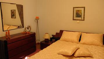 A bedroom with a bed, dresser, mirror, lamp, and a framed picture on the wall.