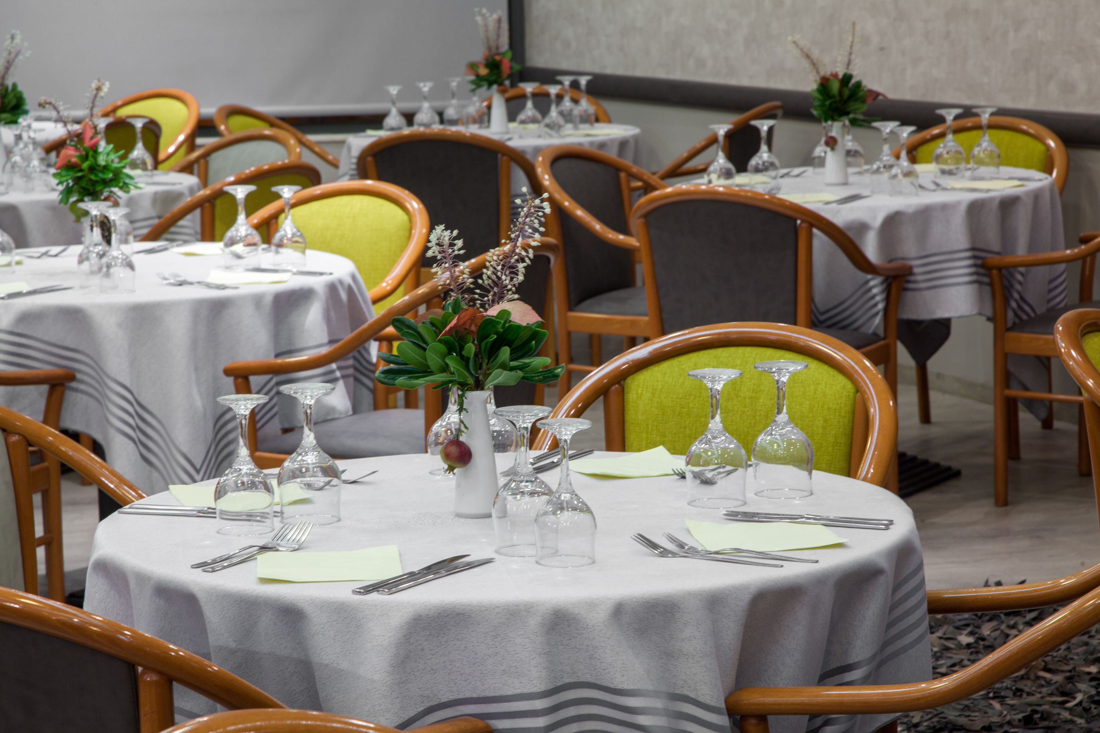 Uma sala de conferência com mesas redondas, cadeiras e centros de mesa.
