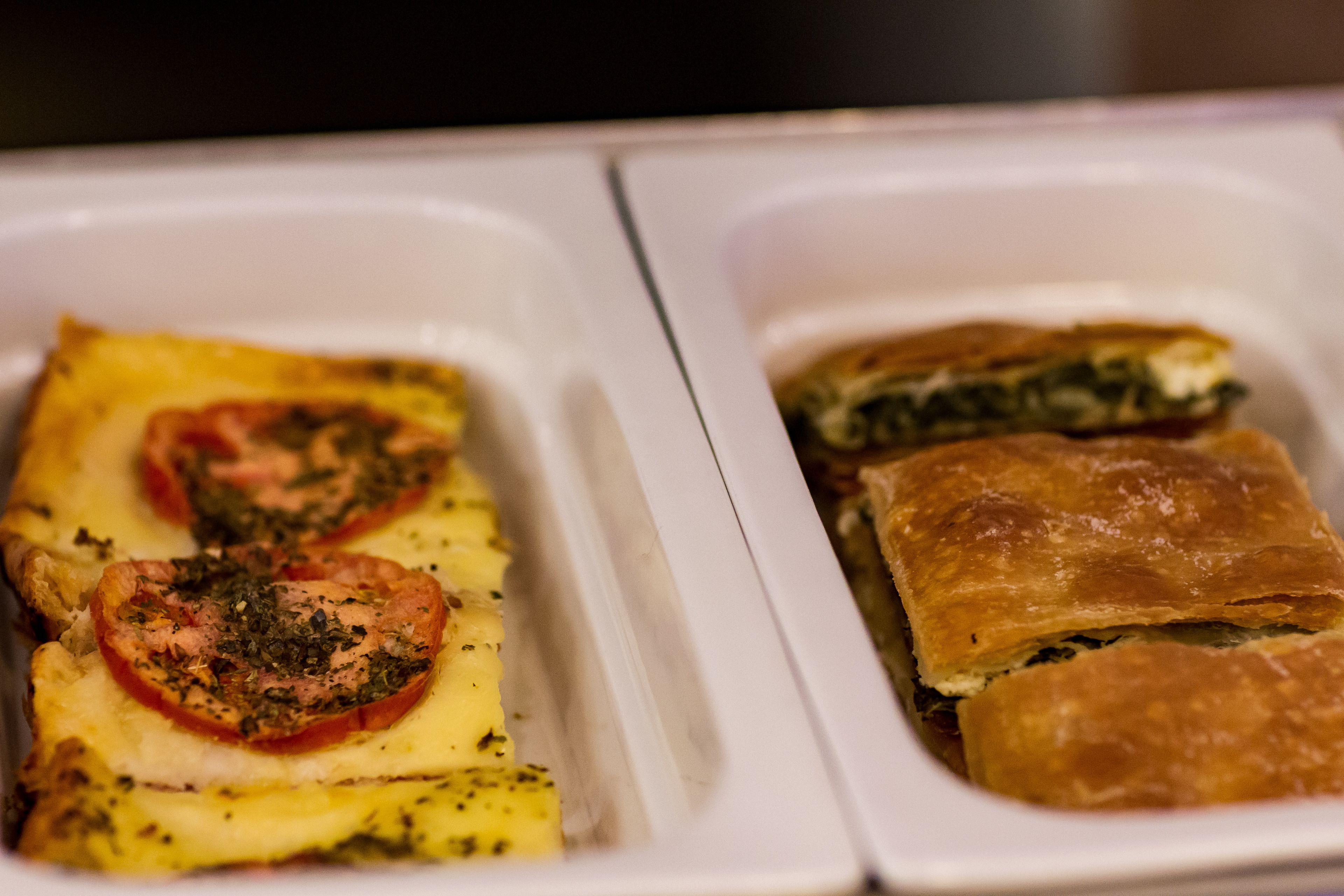 A tray with two types of baked dishes, one with tomatoes and cheese, and another with spinach.