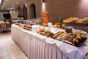 A buffet with various food items including fruits, pastries, and sandwiches.