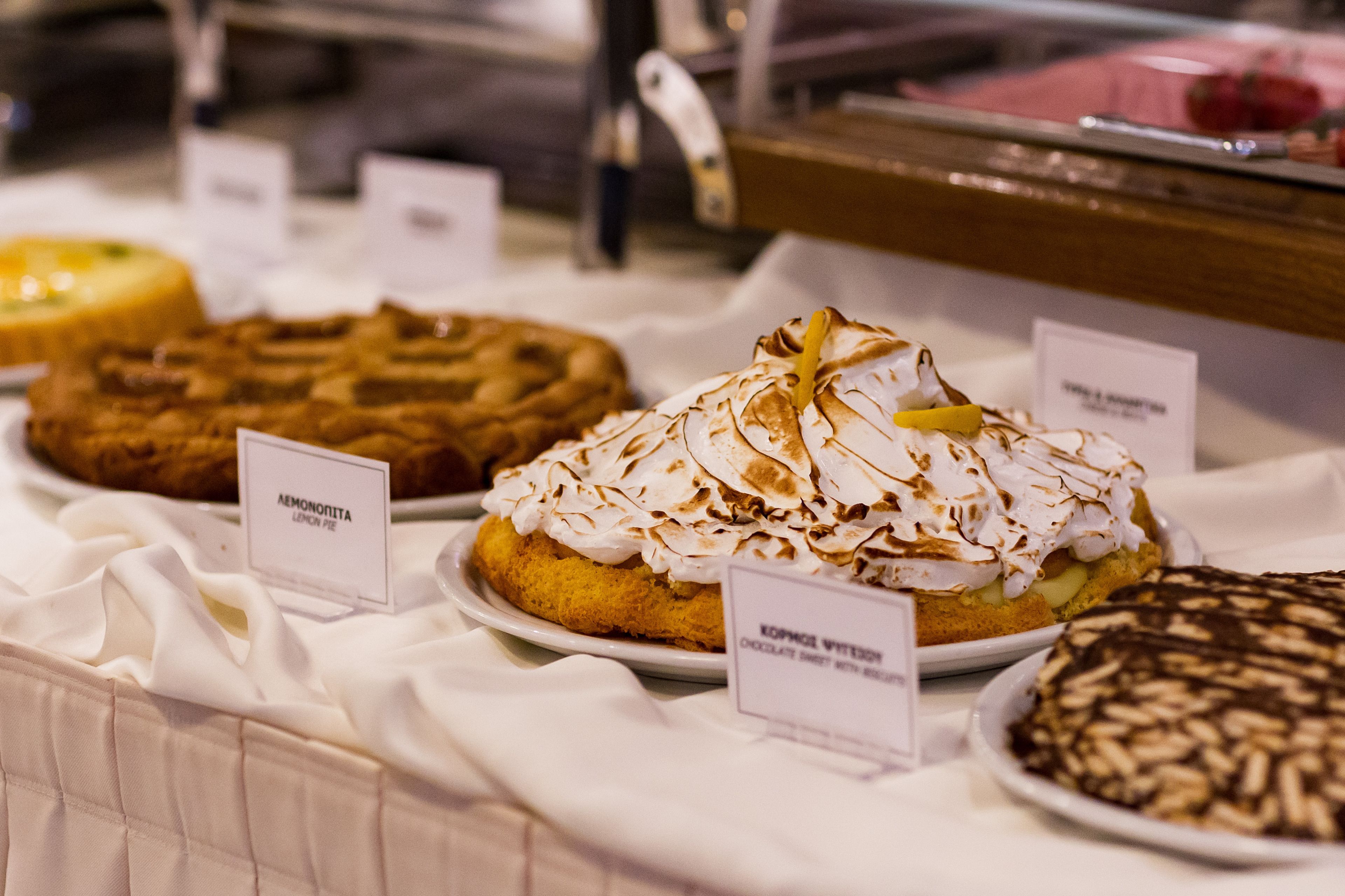 Un présentoir de desserts avec divers gâteaux et pâtisseries, chacun étant accompagné d’une étiquette indiquant son nom.