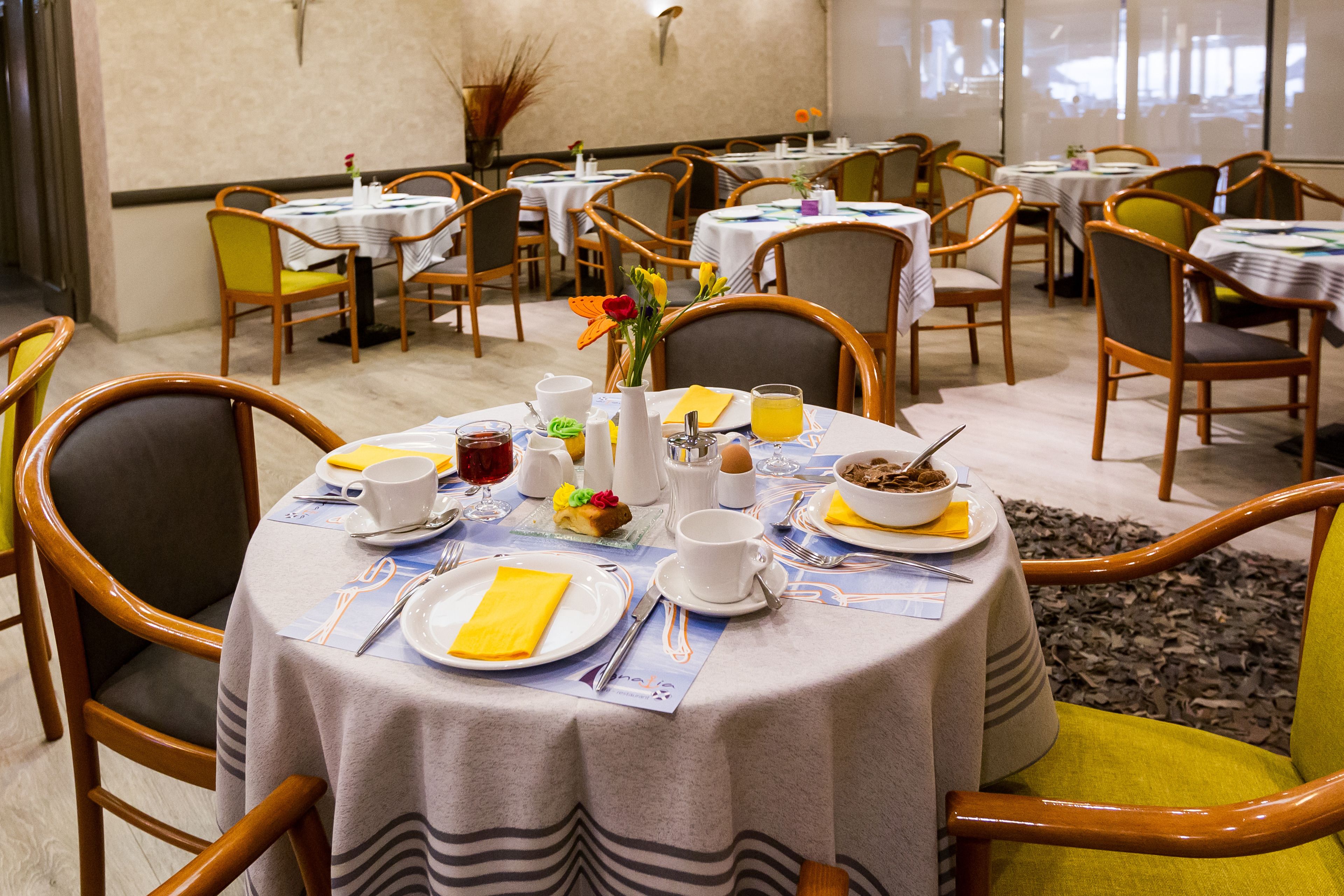 A dining area with round tables, chairs, and breakfast items.