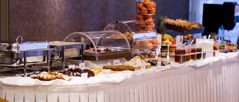 A buffet with various food items and a fruit display.