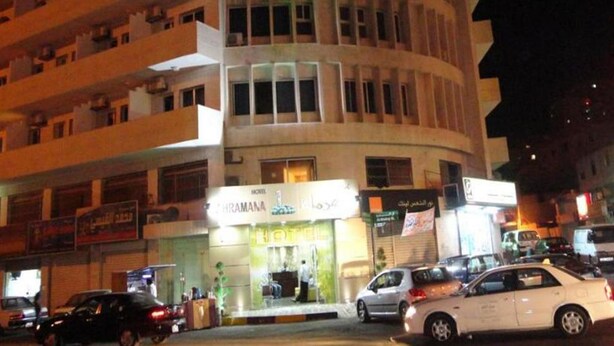 A hotel with multiple floors, a ground-level entrance, and several cars parked in front. - Kahramana Hotel (Amman)