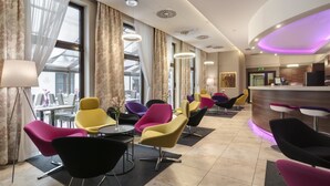 A modern hotel lobby with colorful chairs, a reception desk, and large windows with sheer curtains. - Golden Tulip Krakow City Center (Kraków)