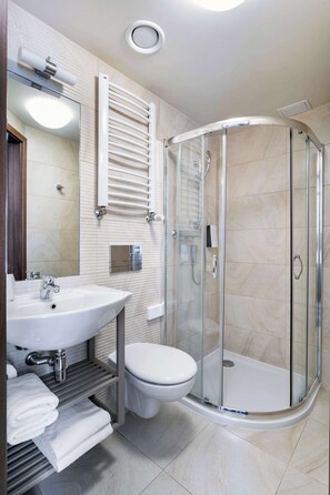A modern bathroom with a glass-enclosed shower, a sink with a mirror, and a toilet. - Golden Tulip Krakow City Center (Kraków)