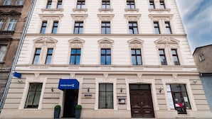 A multi-story building with a classical architectural style, featuring a central entrance with a sign for a hotel and restaurant. - Golden Tulip Krakow City Center (Kraków)