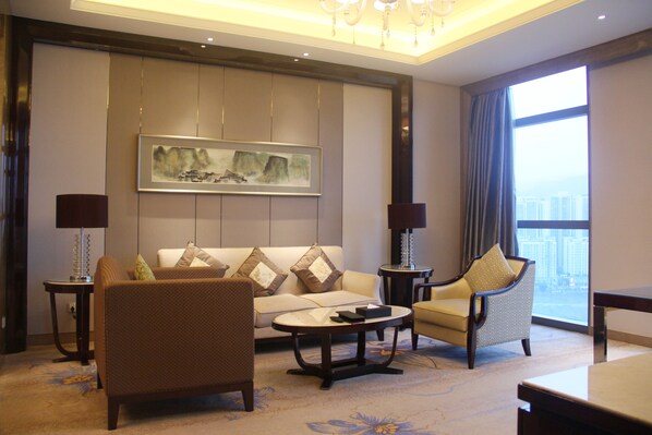 A modern living room with a sofa, armchairs, a coffee table, and a painting on the wall. - Doubletree by Hilton Chongqing Wanzhou (Chongqing)