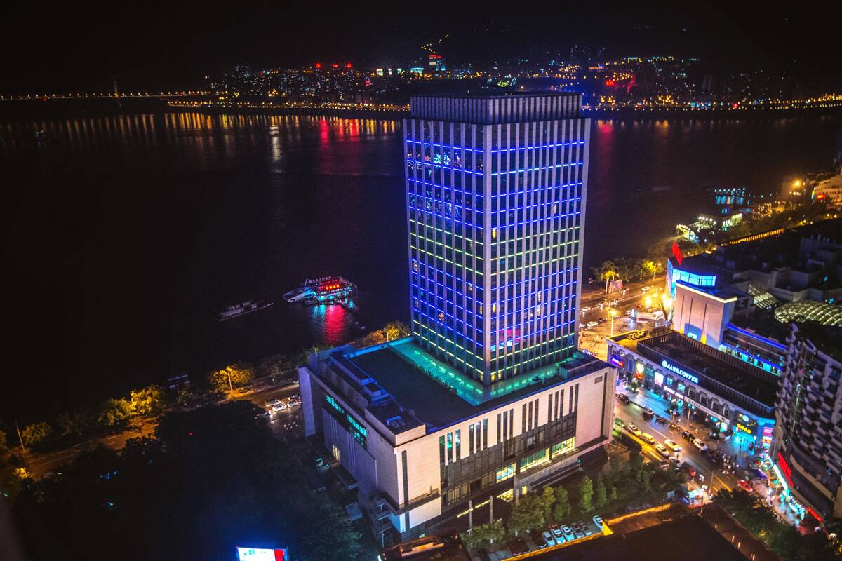 A high-rise building with a modern design, featuring a prominent glass facade and illuminated blue lighting.