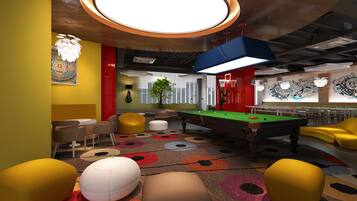 A pool table with surrounding seating, a bar area, and a mural on the wall.