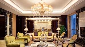Un salon luxueux agrémenté d’un lustre, de fauteuils confortables et d’un grand miroir.