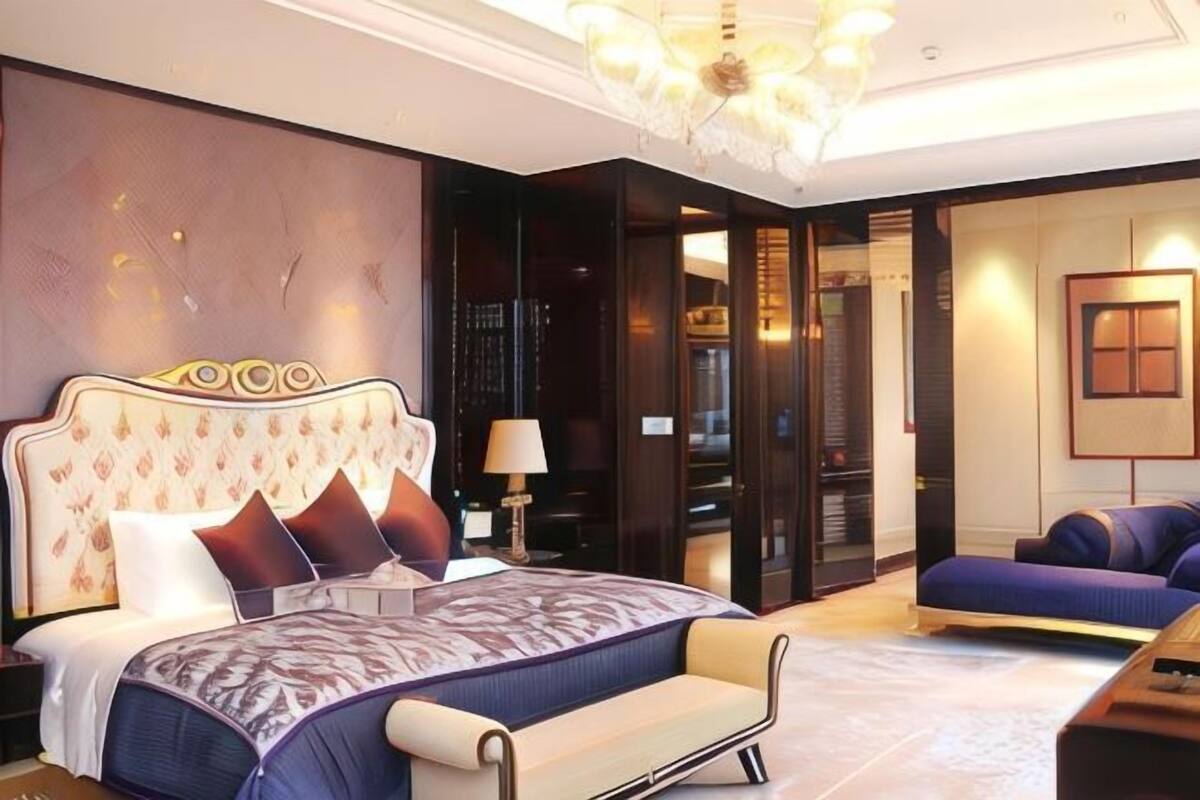 A bedroom with a large bed, a sofa, a chandelier, and a walk-in closet.