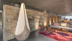 Un vestíbulo moderno con pared de piedra, un sillón colgante, un conjunto de sofás y una mesa de centro.