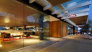 Exterior de un hotel moderno con paredes de vidrio, interiores de madera y un letrero de restaurante visible.