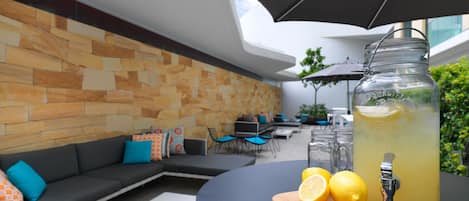 Un espace extérieur aménagé avec un design moderne, comprenant un mur en pierre, une table noire et un distributeur de boissons en verre.