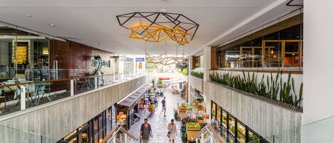 Een meerlaags winkelcentrum met een centrale gangpad, glazen balustrades en een modern plafondontwerp.
