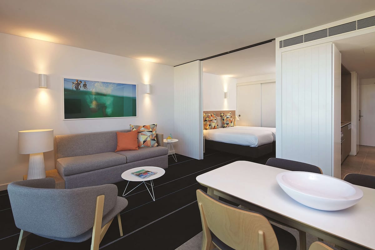 Une chambre d’hôtel moderne équipée d’un canapé, d’une petite table, d’une table à manger et d’un lit.