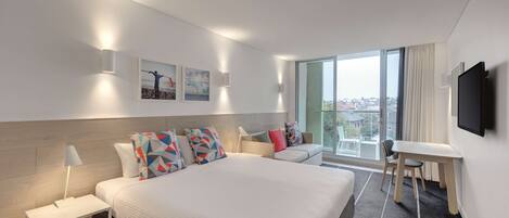 A modern hotel room with a large bed, a desk, and a view of the city.
