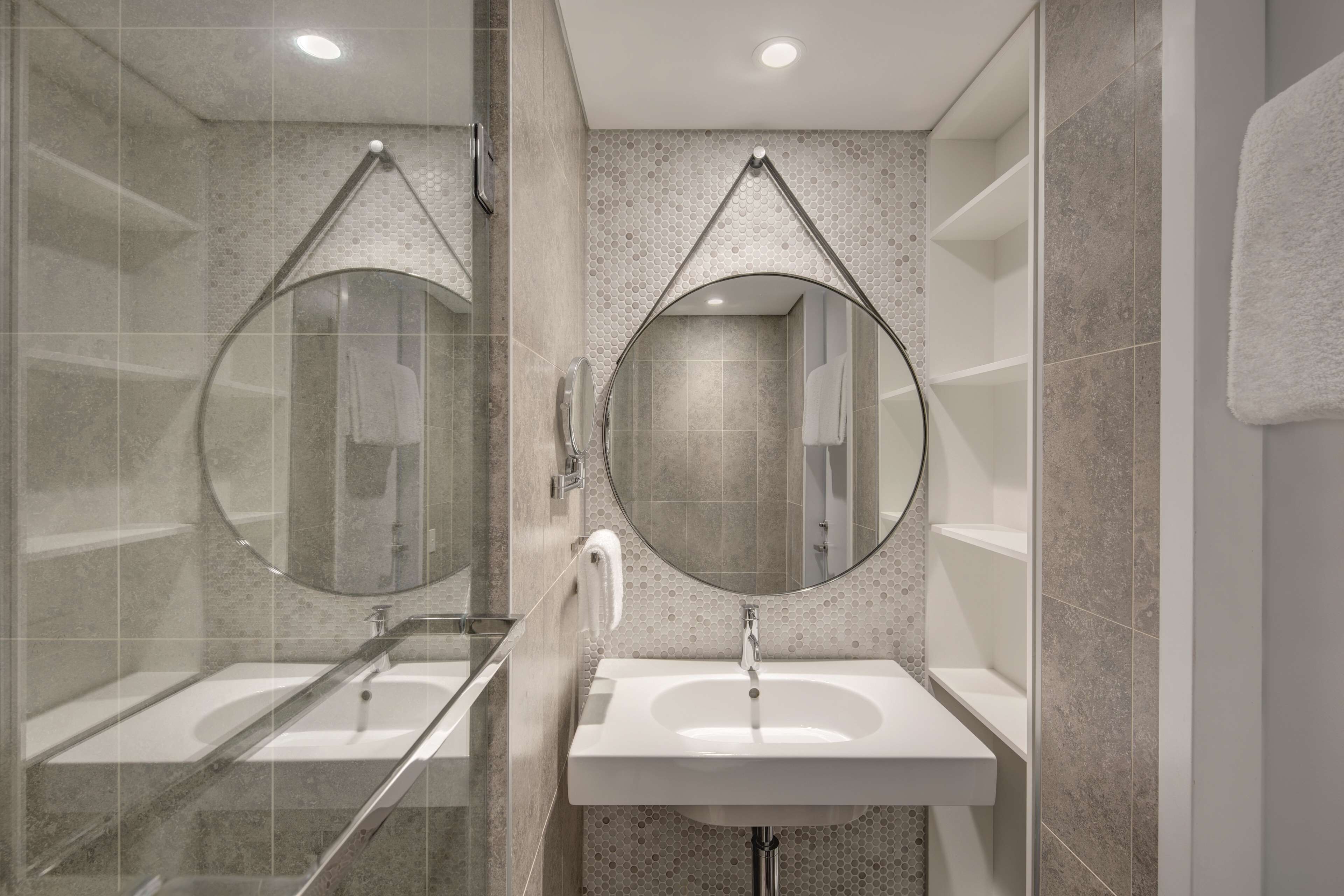 A modern bathroom with two sinks, a glass shower enclosure, and a large mirror above each sink.