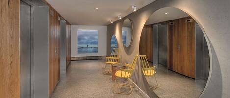 Un interior moderno con vista al mar, que presenta un largo pasillo, paredes de madera y un espejo grande que refleja la habitación.