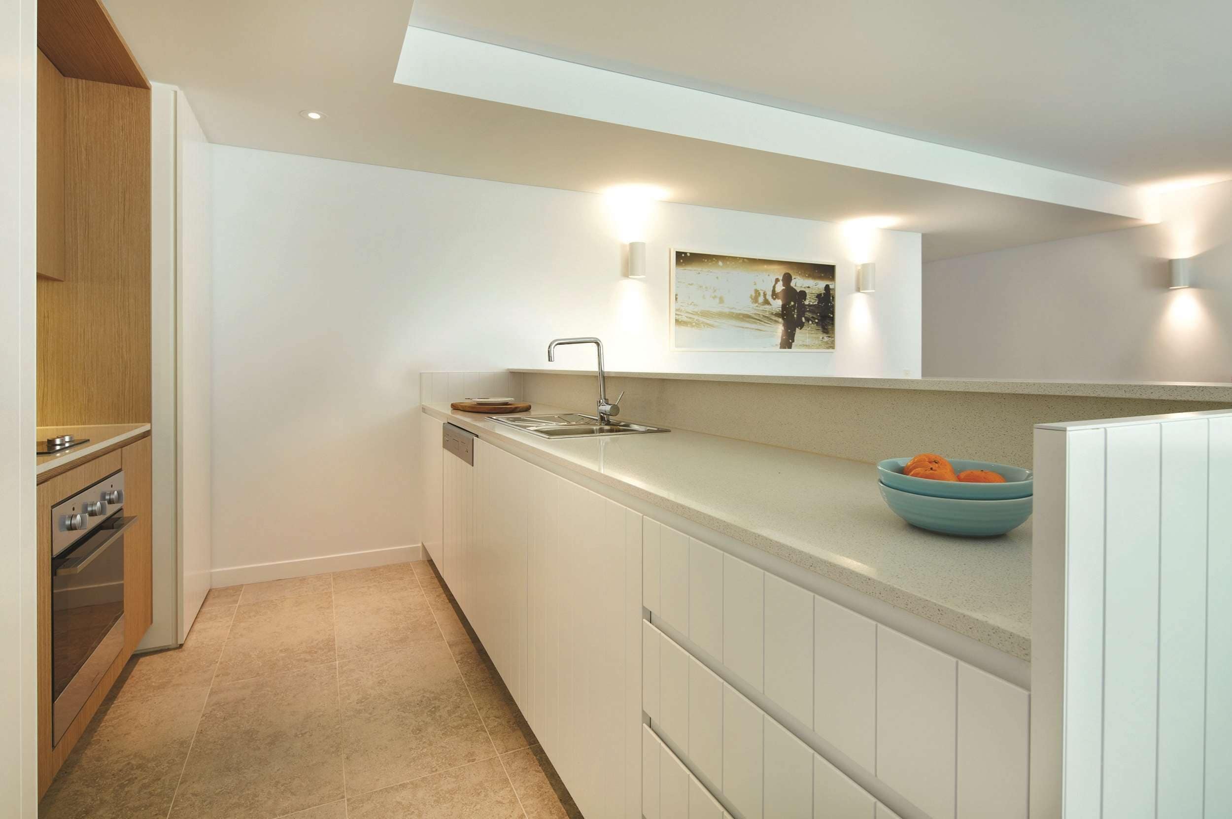 A modern kitchen with white cabinetry, a stainless steel sink, and a light-colored countertop.