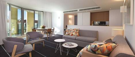 A modern living room with a sofa, two armchairs, a coffee table, and a dining area with a table and chairs.