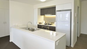 Una cocina moderna con una isla blanca, electrodomésticos de acero inoxidable y un horno empotrado.