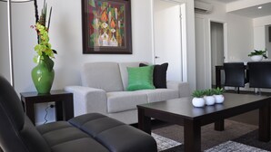 Una sala de estar moderna con un sofá, una mesita de centro y un jarrón verde con flores.