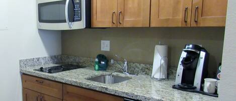A kitchen with wooden cabinets, a microwave, a coffee maker, and a dishwasher.