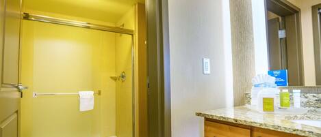 A bathroom with a glass-enclosed shower, a toilet, and a vanity with a marble countertop.
