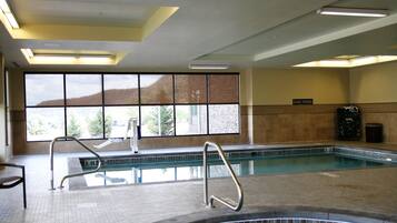En swimmingpool med utsikt över bergen genom stora fönster, en skylt med texten ”Dyka förbjudet” och ett kaklat golv.