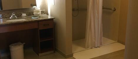 A bathroom with a sink, mirror, and shower.