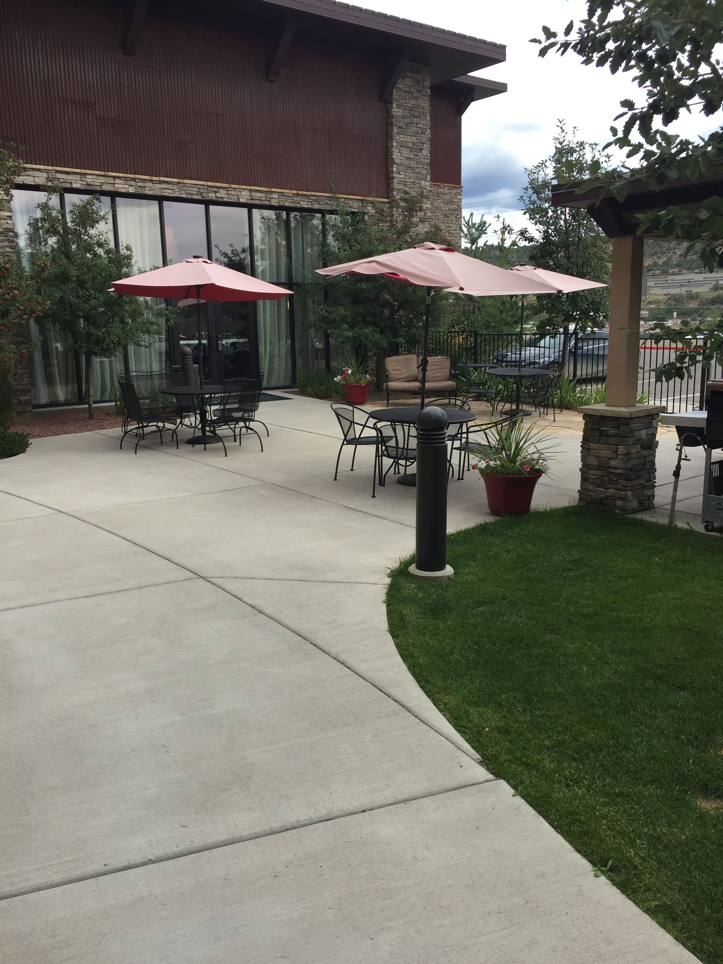An outdoor patio area with tables and chairs, two umbrellas, and potted plants.