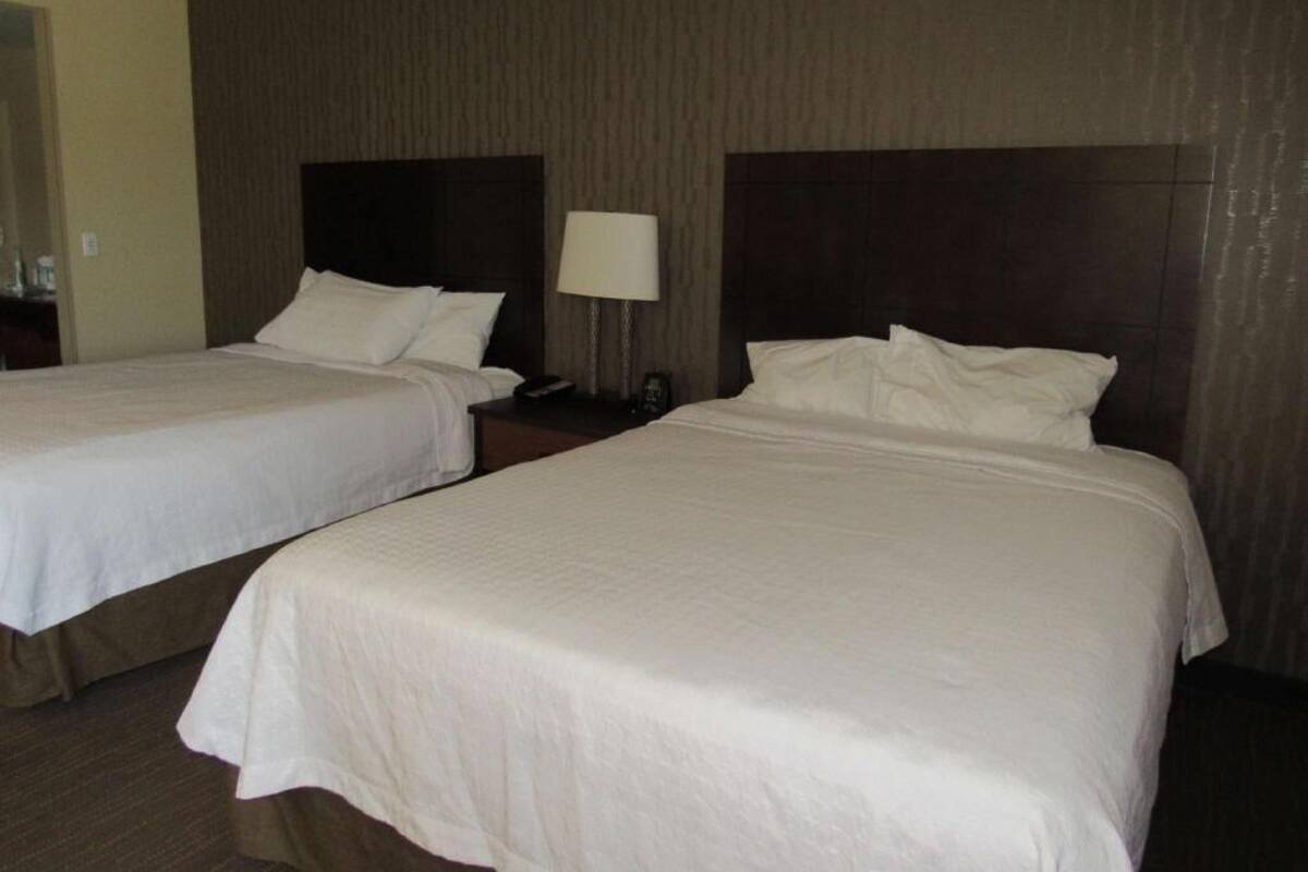 Two double beds with white linens in a hotel room.
