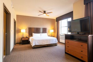 Une chambre d’hôtel comprenant un lit, deux lampes de chevet, un ventilateur de plafond, une télévision et une commode.