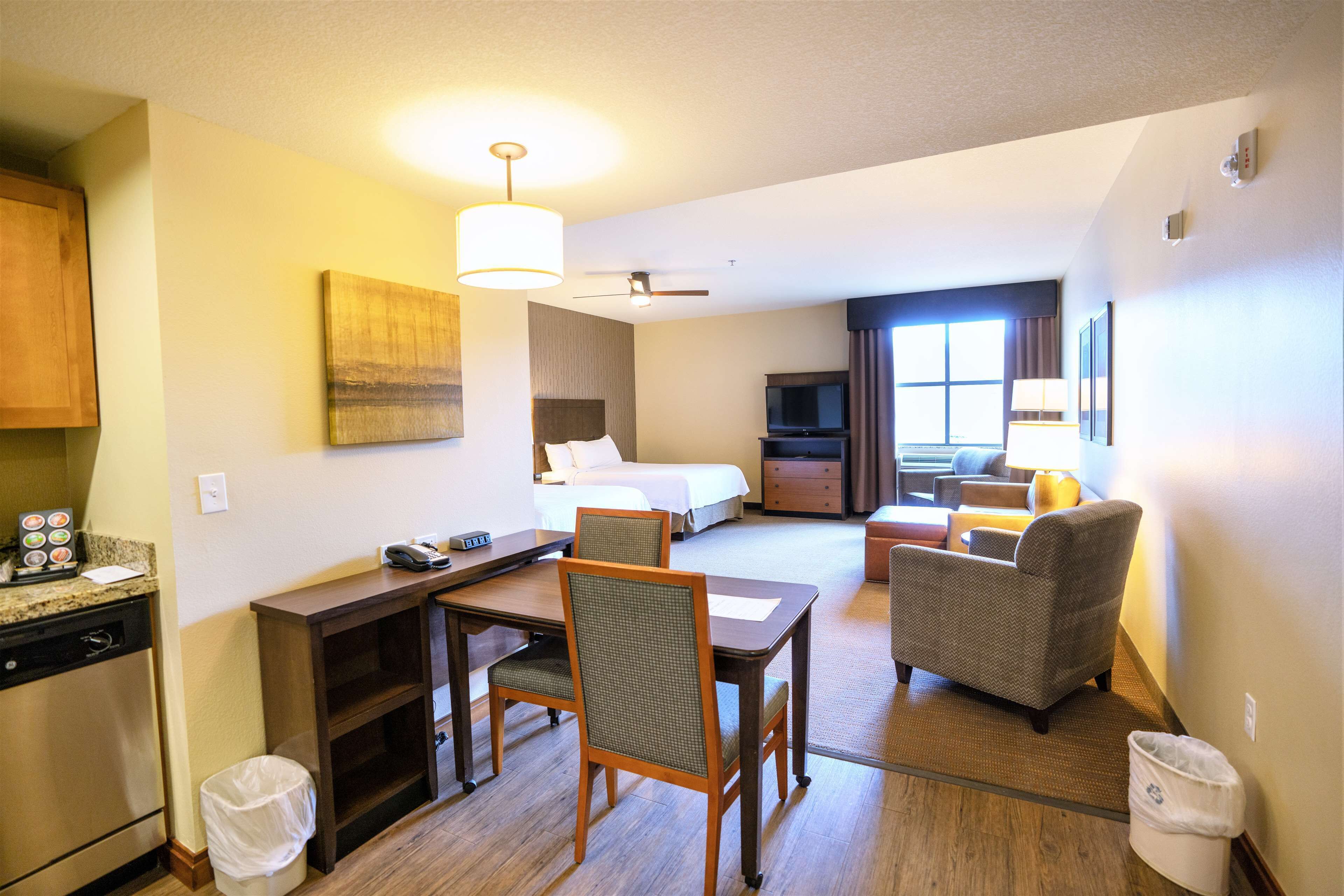A hotel room with a bed, a desk, a chair, a television, and a sofa.